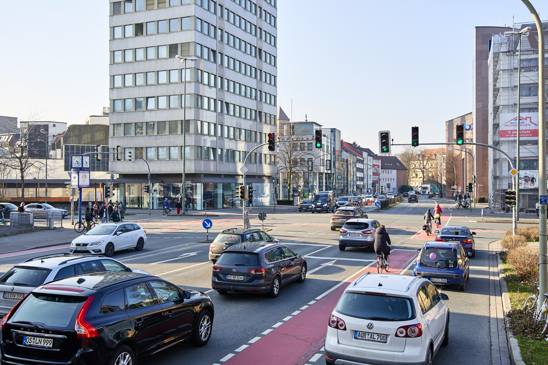 Verkehrsszenario an einer Stadtkreuzung mit mehreren Autos und einem modernen Gebäude im Hintergrund.