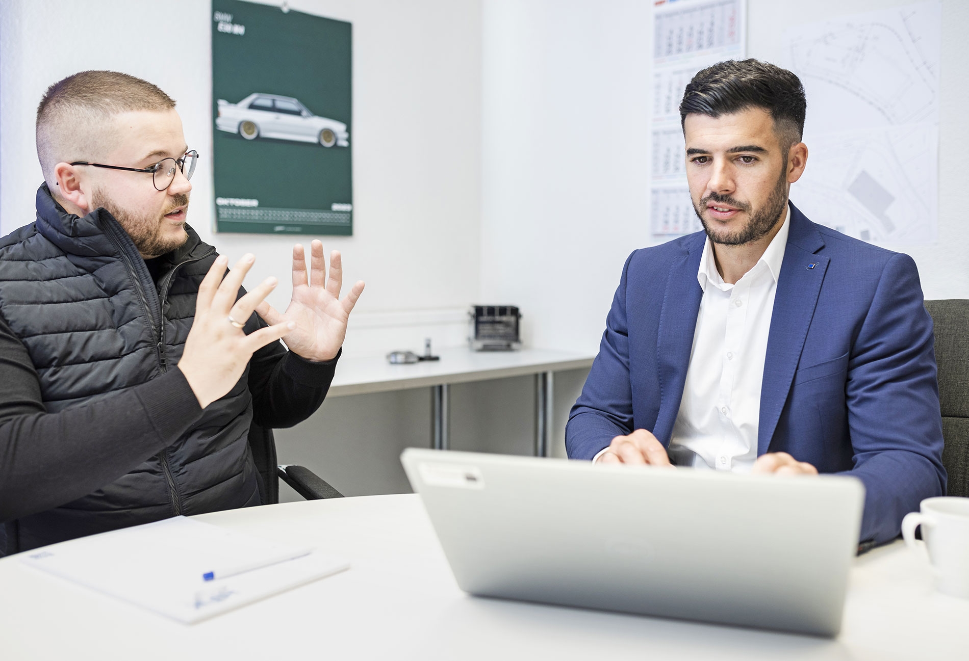 Trumpf-Außendienstmitarbeiter Felix Kuster besucht die Metalltechnikfirma HFK in Willstätt bei Offenburg. Mit einem Mitarbeiter sitzt er im Gespräch am Tisch. Vor ihm steht sein geöffneter Laptop.