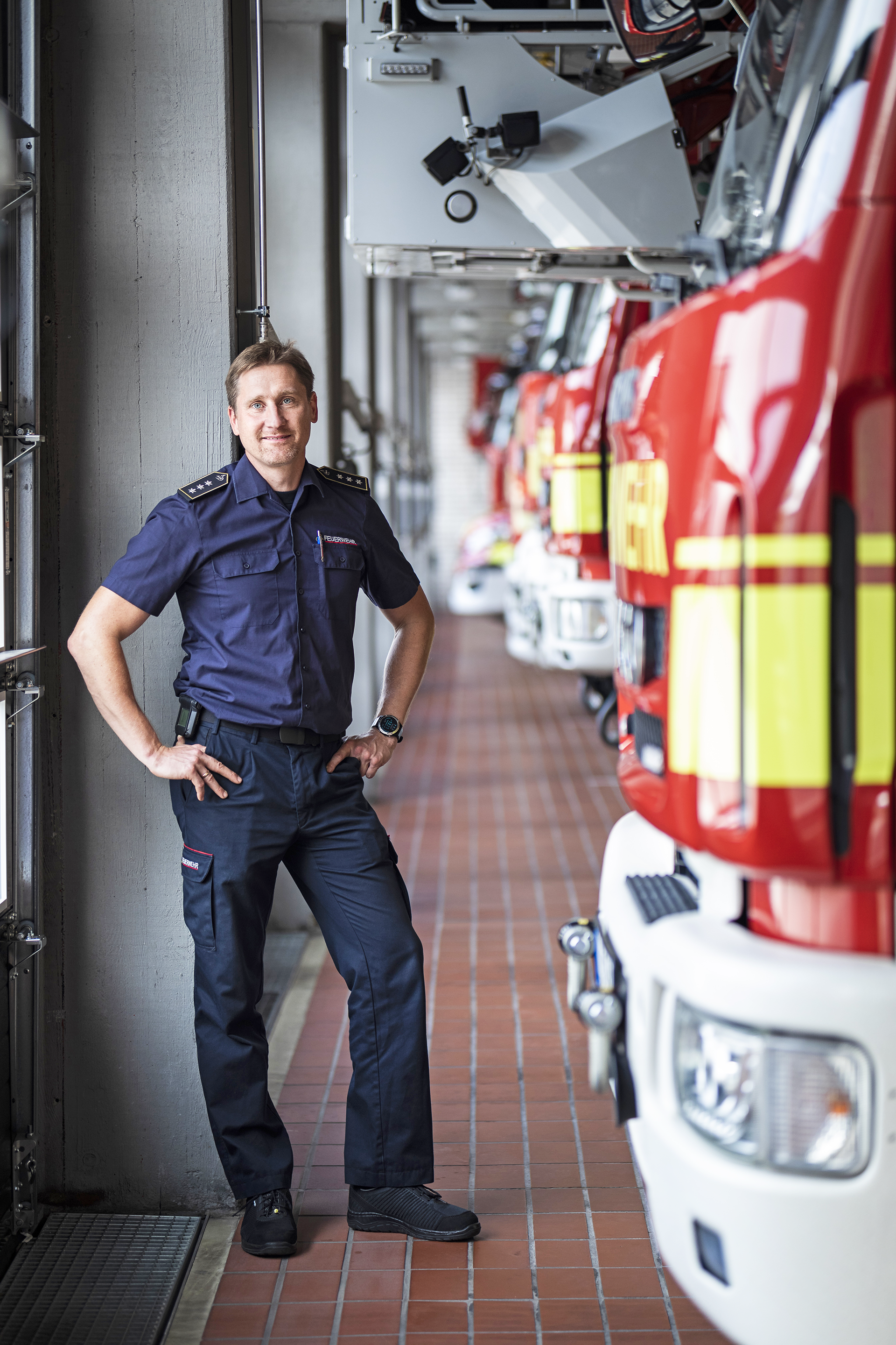 Portrait von Tobias Güntner, Leiter der ILS (Integrierte Rettungs- und Feuerwehrleitstelle) der Stadt Ulm und des Alb-Donau-Kreises, neben den Einsatzfahrzeugen in der Fahrzeughalle der Ulmer Hauptfeuerwache an der Keplerstraße.