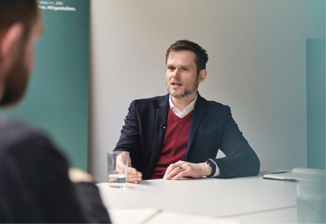 Dr. Matthias Peissner ist frontal an einem Tisch sitzend zu sehen. Er ist im Gespräch mit seinem Gegenüber, den man leicht im Anschnitt von hinten sieht.