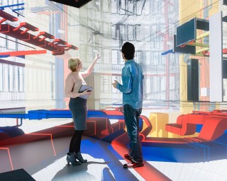 Zwei Personen diskutieren vor einer digitalen Visualisierung eines Gebäudemodells mit farblich hervorgehobenen technischen Anlagen – Symbolbild für digitale Planung, BIM und innovative Technologien im industrialisierten Bauen.