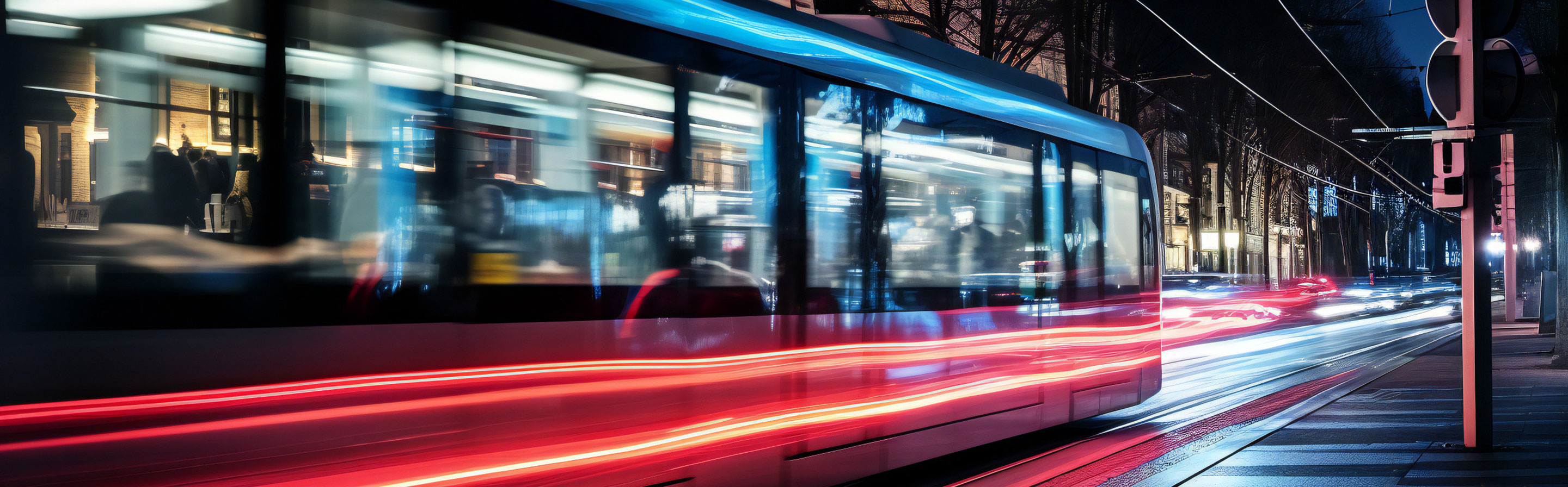 Eine Straßenbahn fährt nachts durch eine Straße in einer Stadt.