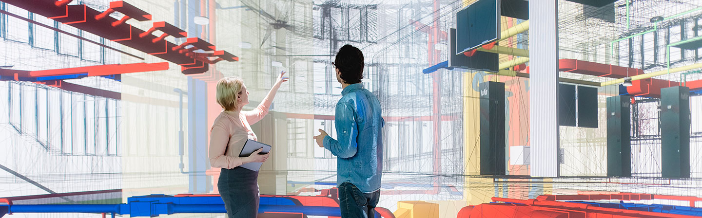 Zwei Personen diskutieren vor einer digitalen Visualisierung eines Gebäudemodells mit farblich hervorgehobenen technischen Anlagen – Symbolbild für digitale Planung, BIM und innovative Technologien im industrialisierten Bauen.