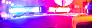 Police car in action with blinking light and siren signal at night in the city. Blurred bokeh background, public lighting lamps.